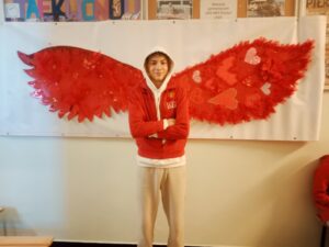 uczniowie na tle skrzydeł, zrobionych na zajęciach